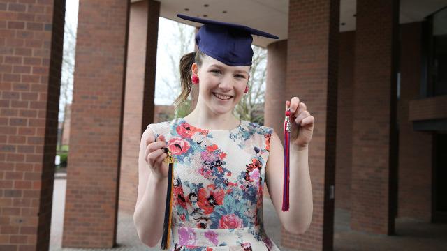 Early College student holds both high school and college tassels.