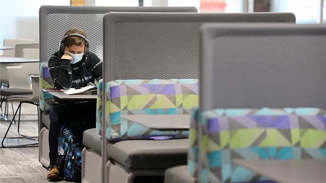 Student wearing a face mask studying in the newly remodeled library space